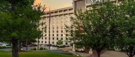 A large hotel with a prominent sign, surrounded by well-maintained lawns and trees.