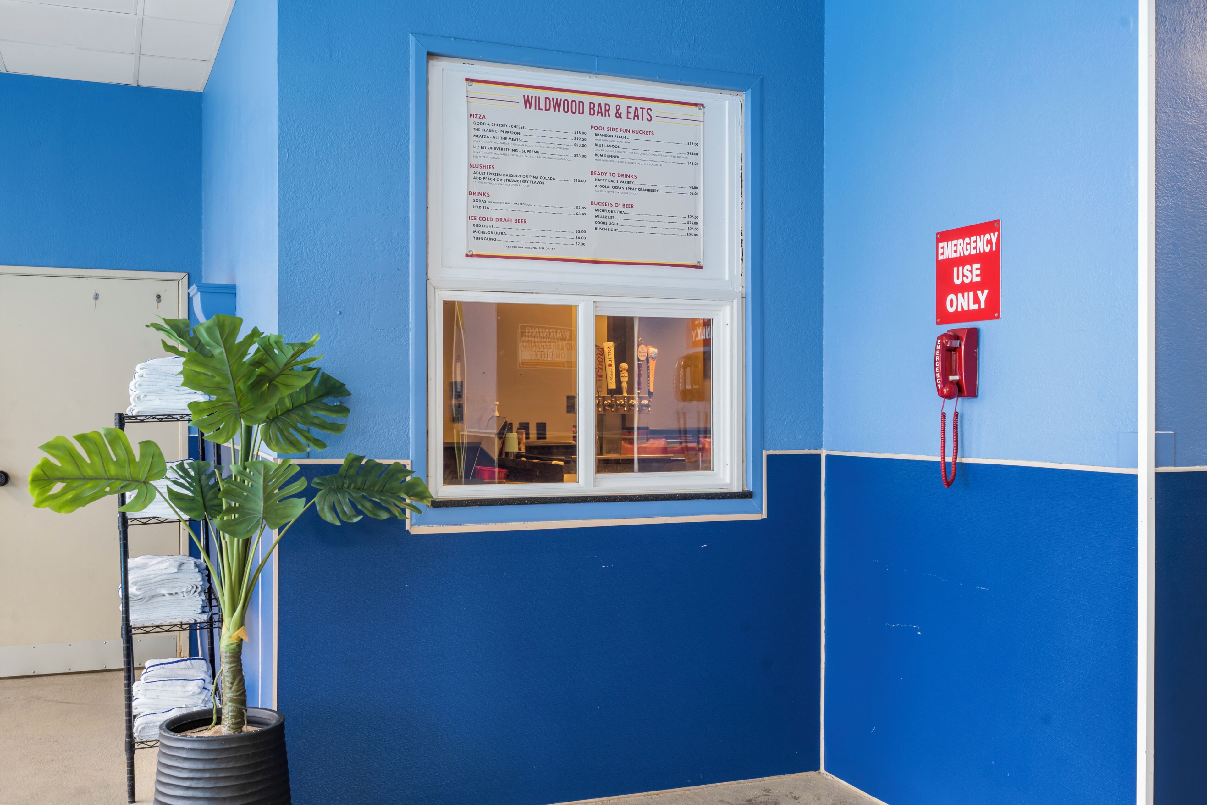 Een menubord van Wildwood Bar & Eats, een brandmelder en een potplant.