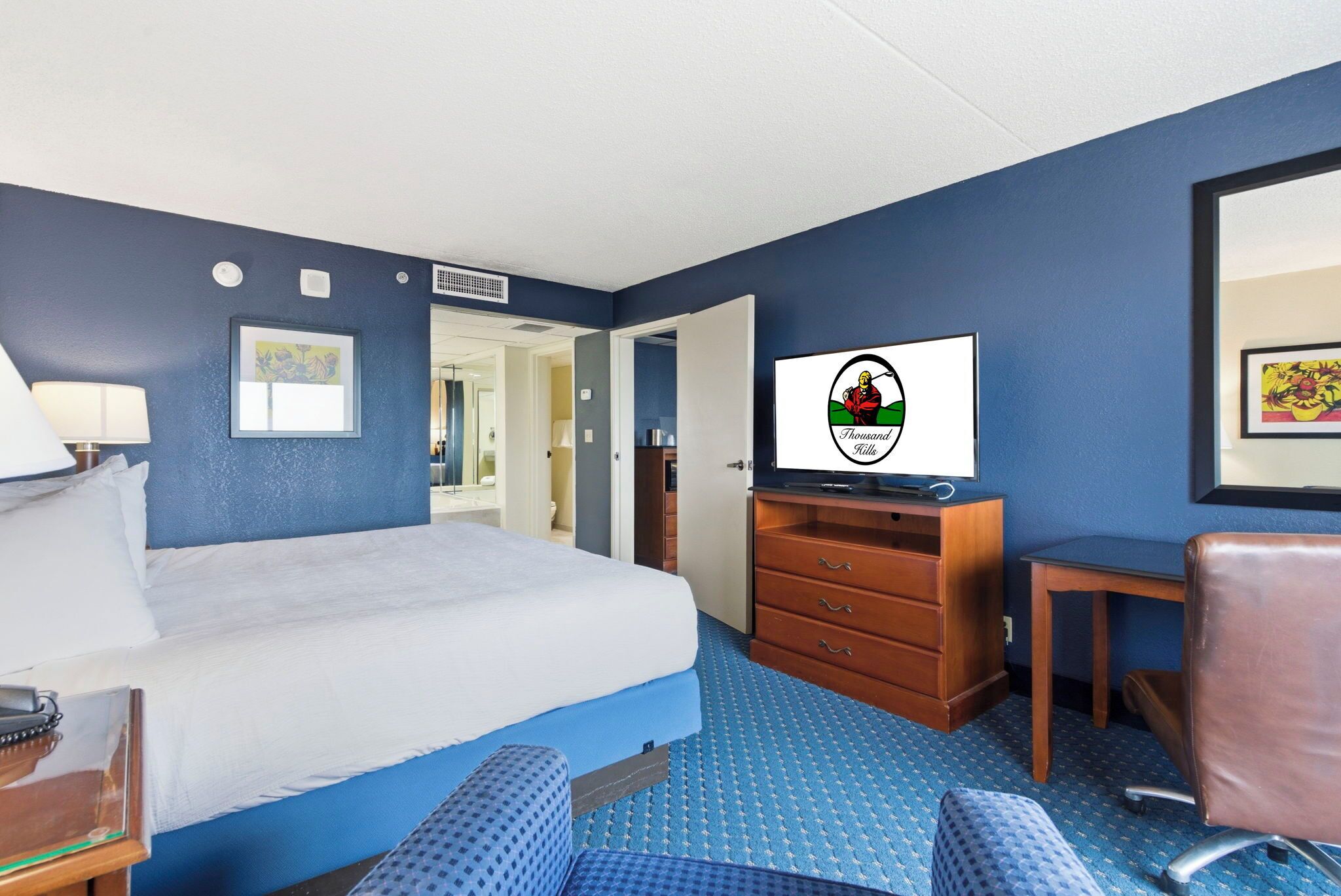 A hotel room with a bed, a desk, a chair, a television, and a wardrobe.