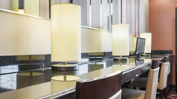A hotel reception area with a marble counter, multiple chairs, and a large mirror reflecting the interior.