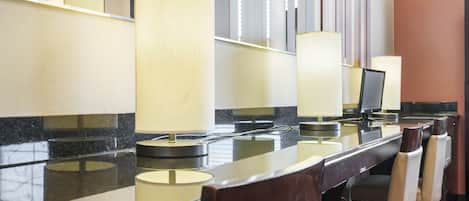 A hotel reception area with a marble counter, multiple chairs, and a large mirror reflecting the interior.
