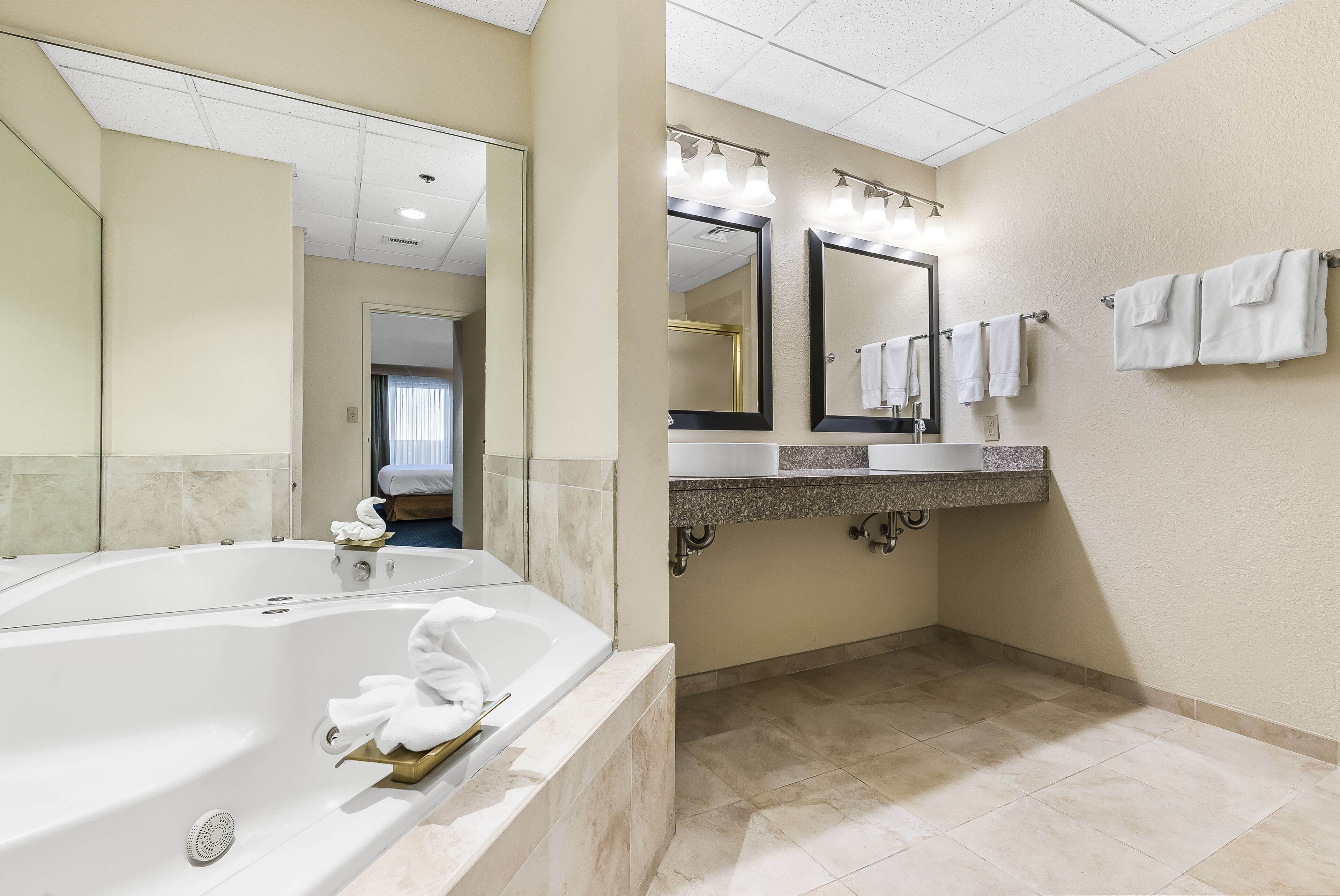 A modern bathroom with a large bathtub, a vanity with a mirror, and a shower area.