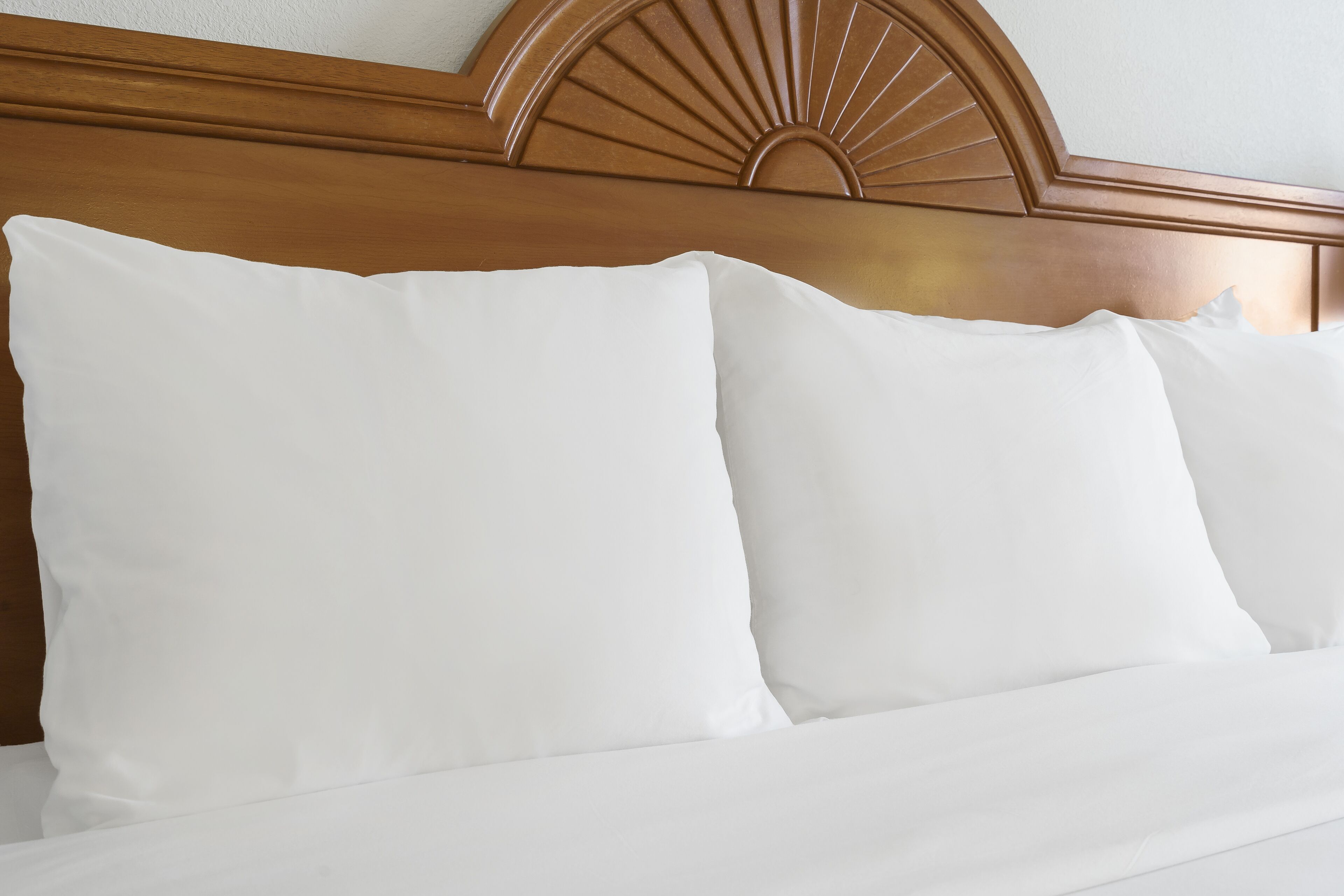 A bed with a wooden headboard and white bedding.