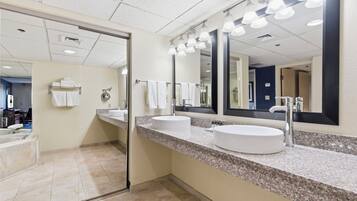 A modern bathroom with two sinks, a large mirror, and a towel rack.