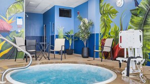 Zona de piscina con una pared azul, sillas y plantas en macetas.