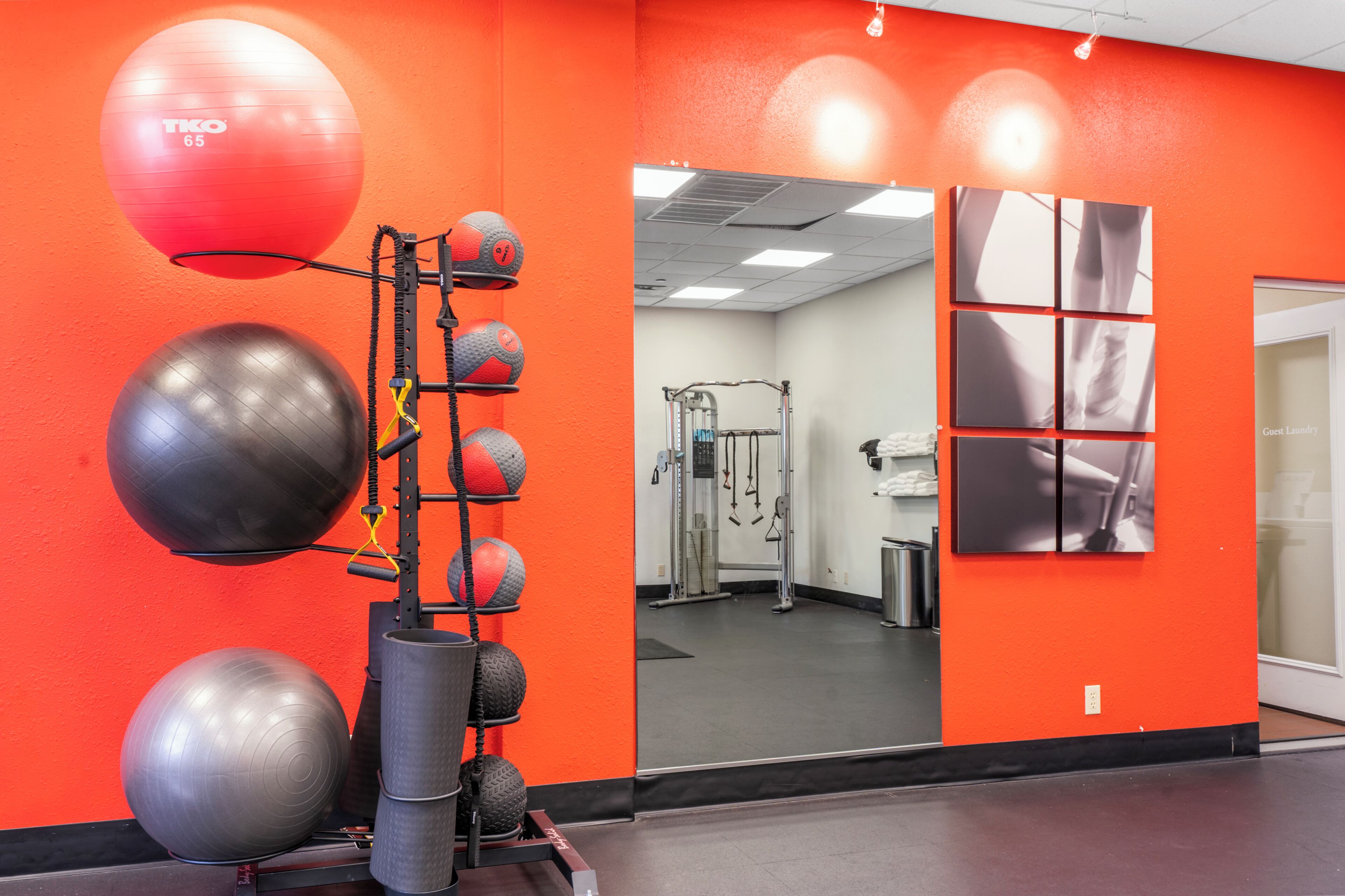 Une salle de sport avec des murs orange, des ballons d’exercice et un miroir.
