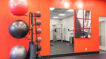 Une salle de sport avec des murs orange, des ballons d’exercice et un miroir.