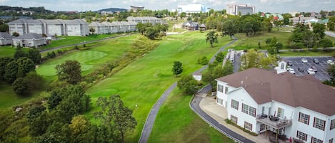 Un campo de golf con un club de campo y edificios residenciales al fondo.