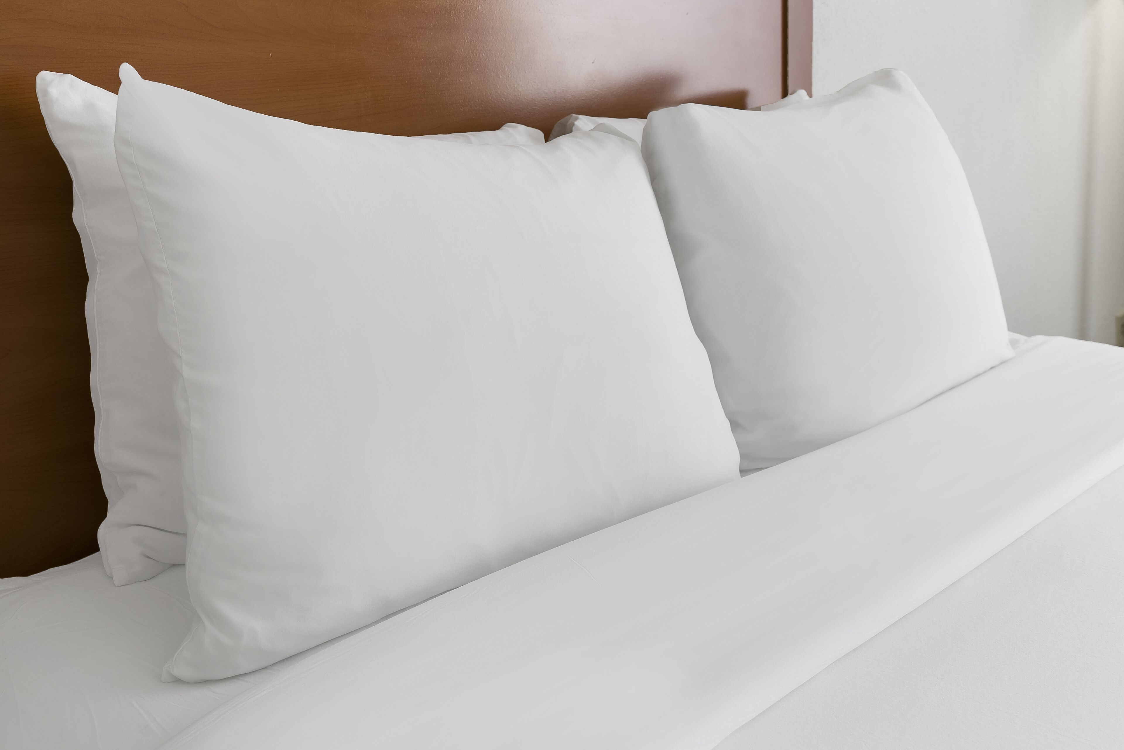 A neatly made bed with white bedding and pillows.
