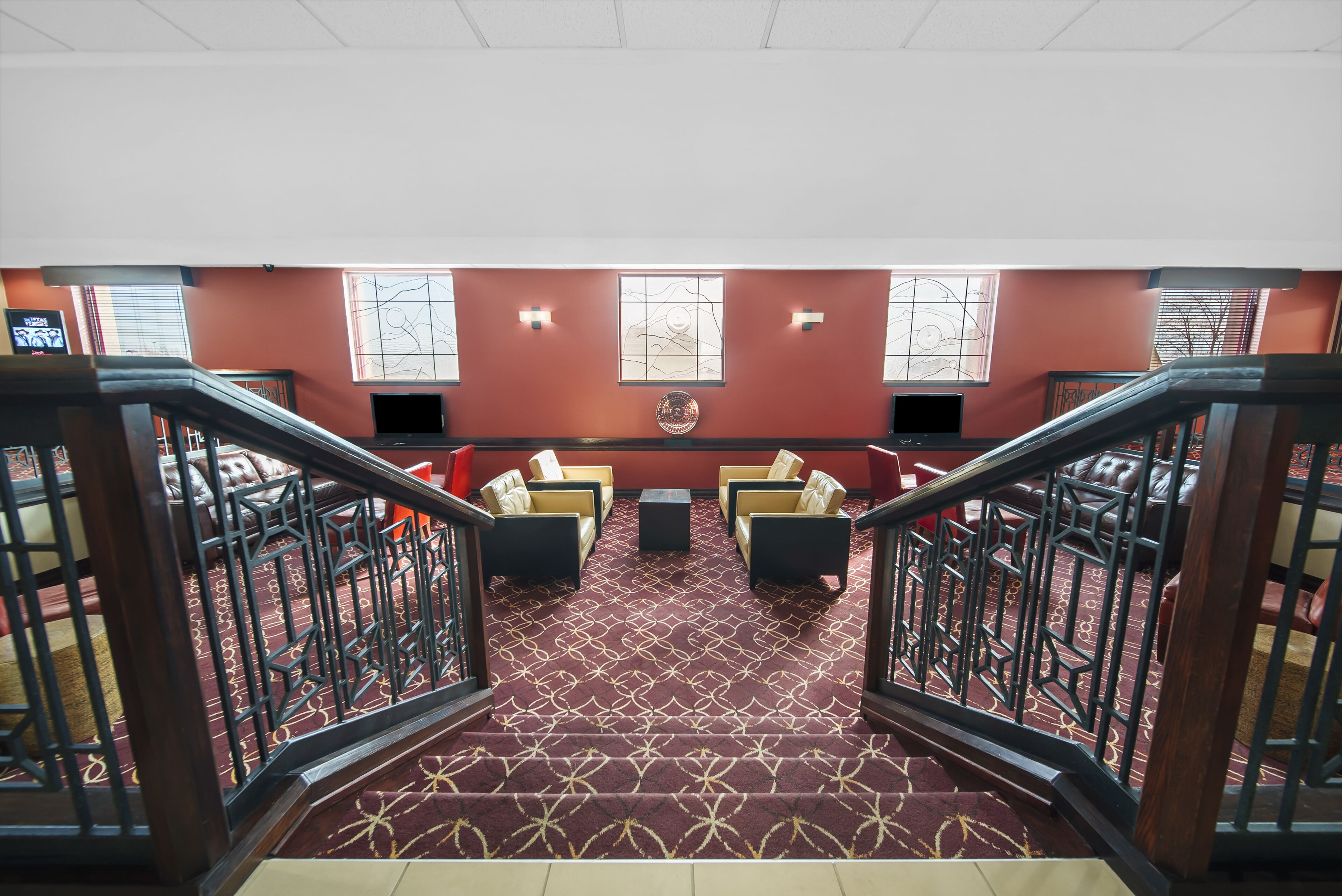 A hotel lobby with a red carpet, two sofas, a coffee table, and a decorative wall piece.