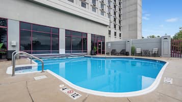 An outdoor swimming pool with a 4ft depth limit, adjacent to a building with large windows and a grey exterior.