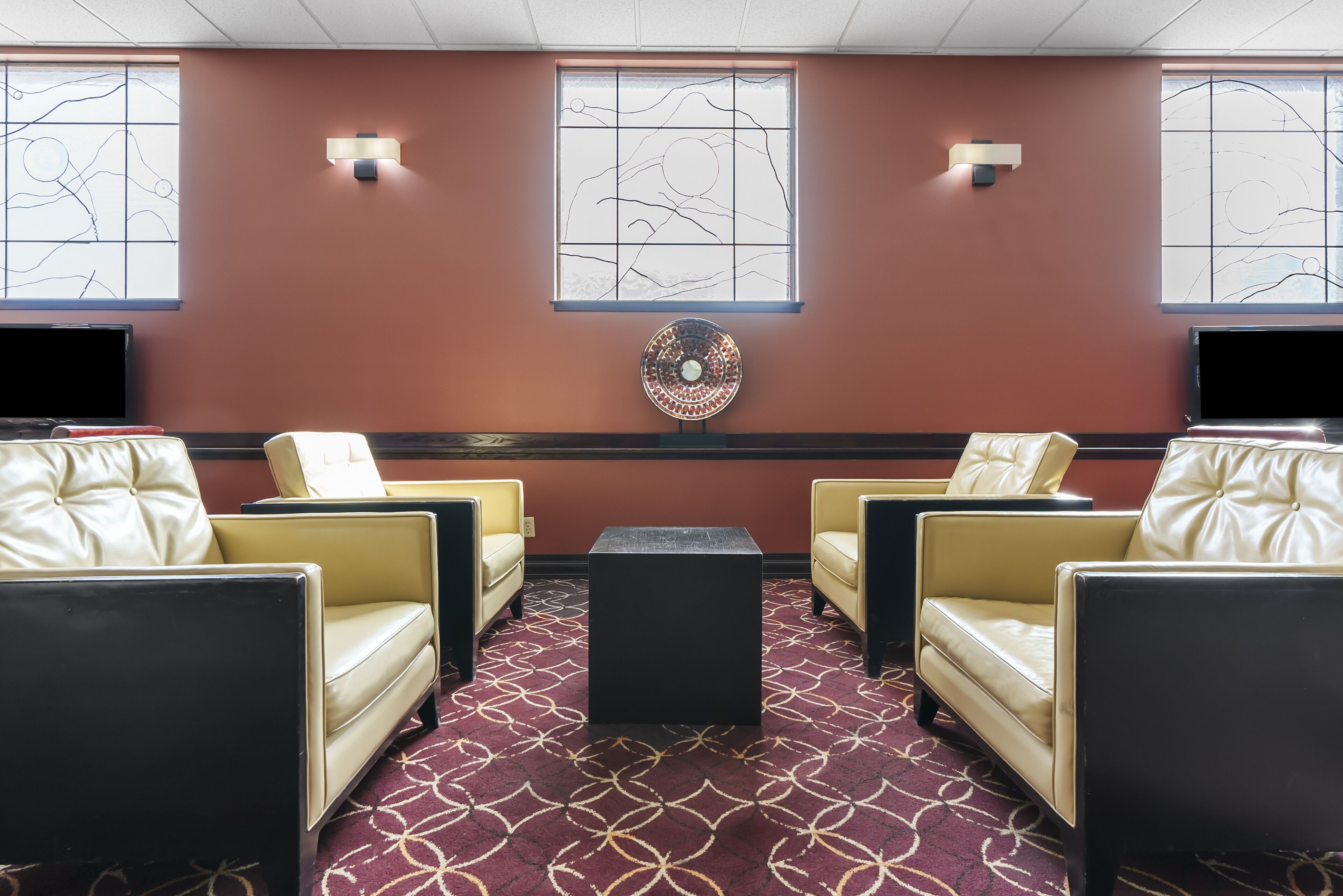 A room with four leather chairs, a central black table, and a patterned carpet.