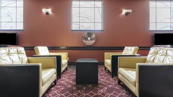 A room with four leather chairs, a central black table, and a patterned carpet.