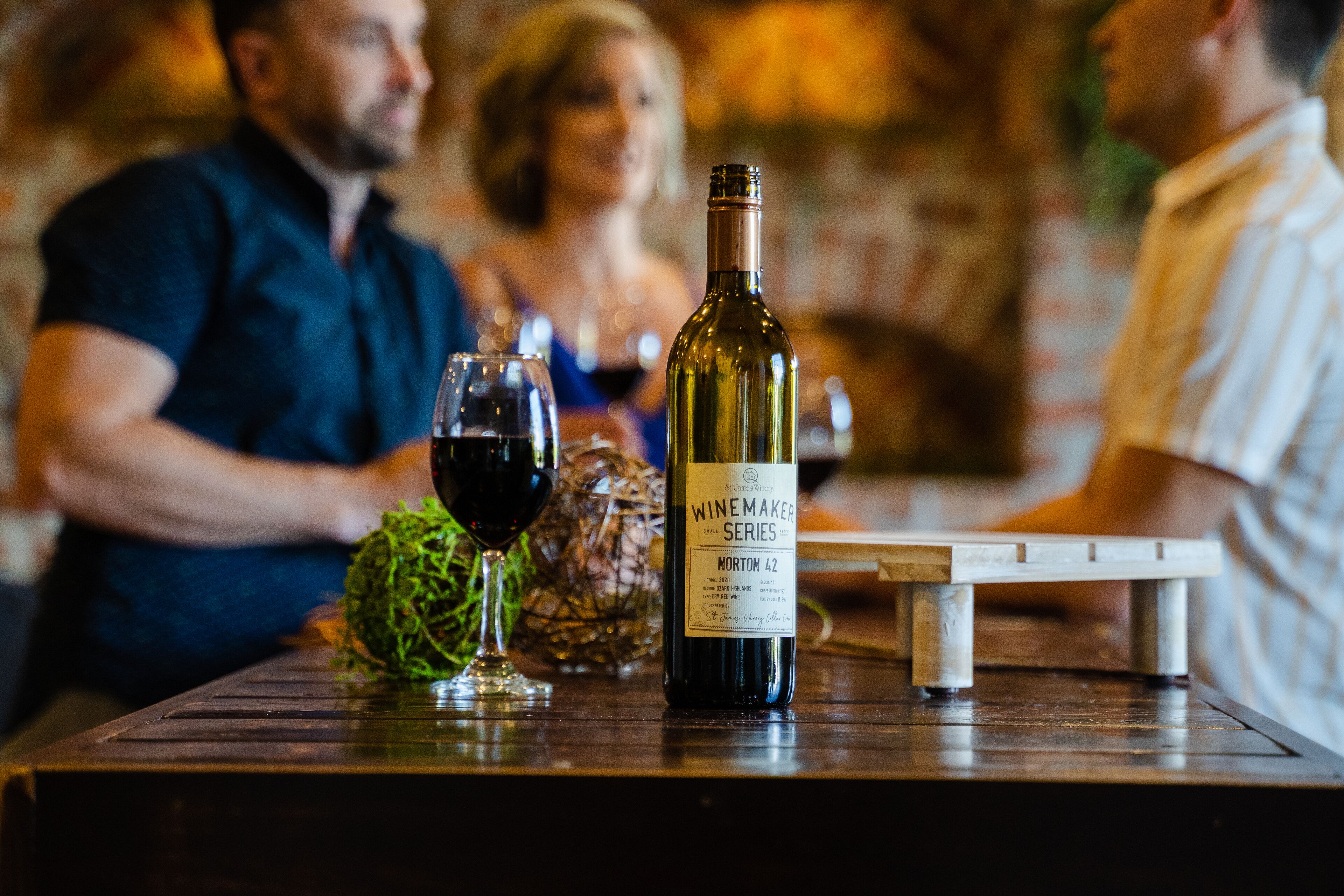 Une bouteille de vin sur une table, avec des verres et un objet décoratif.