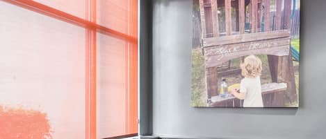 L’intérieur d’un restaurant, avec une grande fenêtre, un tableau accroché au mur et un banc à motifs.