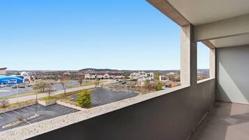 A balcony with a view of a parking lot, buildings, and a clear sky.