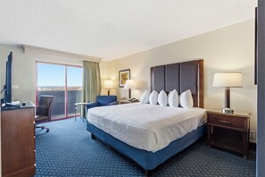 Habitación de hotel con una cama grande, un escritorio, una silla, un televisor y una ventana con vistas.