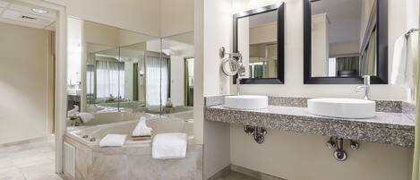 A modern bathroom with a large bathtub, two sinks, and a vanity area.