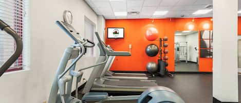 Un gimnasio con cintas de correr, elípticas y pelotas de ejercicio.