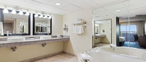 Une salle de bain moderne avec deux lavabos, un grand miroir, une baignoire et un espace douche.