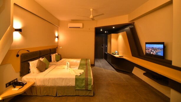 Una habitación de hotel moderna con cama, mesita de noche, televisor y ventilador de techo.