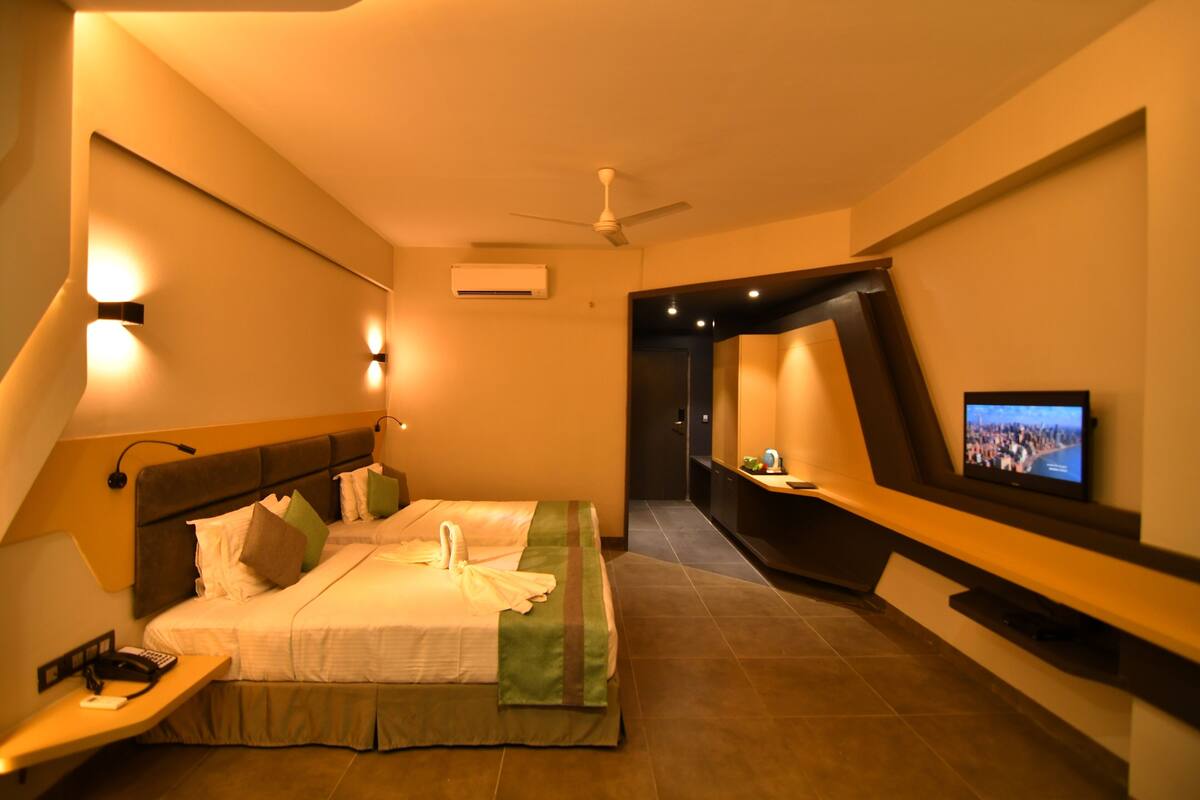Ein modernes Hotelzimmer mit Bett, Nachttisch, Fernseher und Deckenventilator.