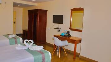 A hotel room with two beds, a desk, a chair, a TV, and a wardrobe.