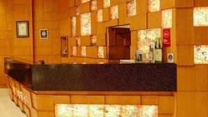 Un área de recepción con pared de madera, mostrador negro y un certificado enmarcado a la izquierda.