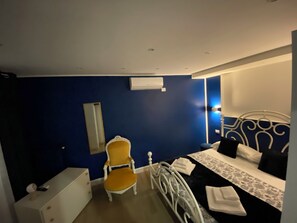 Un dormitorio con cama, una silla, un aparador y un equipo de aire acondicionado.