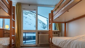A room with bunk beds, a window with a view of a snowy mountain, and a radiator. - In the center of town, close to the ski slopes, 3 rooms, 2 bedrooms for 4 people (Val-d'Isère)