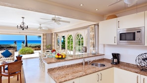 A kitchen with a view of the ocean, a ceiling fan, and a microwave. - Enchanting Beachfront Retreat - Leamington Cottage 1 Bedroom Villa by Blue Sky Luxury (Speightstown)