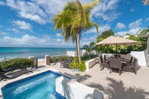 Ein Poolbereich mit Liegestühlen, einem Tisch und Blick auf den Ozean.
