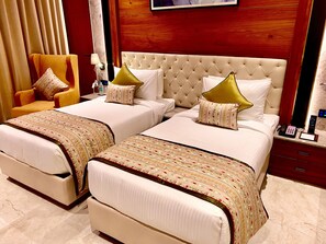 A hotel room with two beds, a chair, a nightstand, and a mirror.