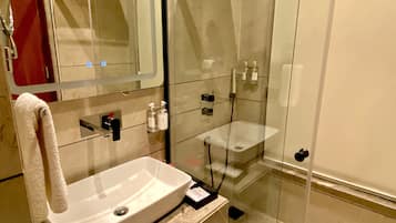 A modern bathroom with a glass-enclosed shower, a white sink, and a mirror.