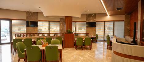 A spacious restaurant with high ceilings, wooden paneling, and a reception desk.