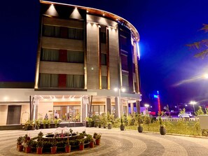 A modern hotel with a curved facade, multiple floors, and a well-lit entrance.