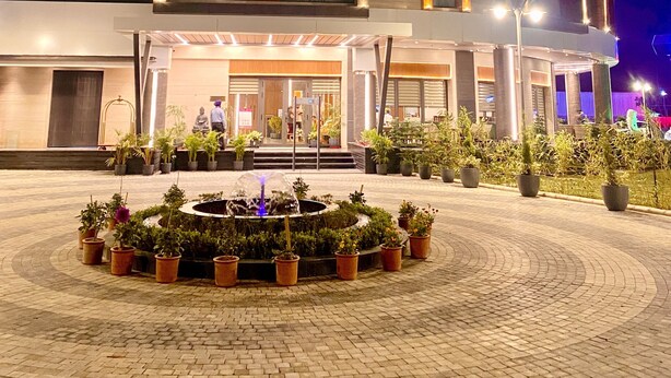 Un hotel moderno con fachada curva, varios pisos y una entrada bien iluminada.