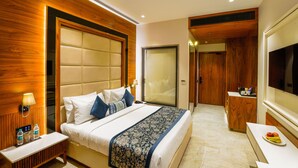 Una habitación de hotel con una cama grande, mesitas de noche, un espejo y un televisor.