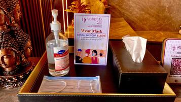 Una botella de gel hidroalcohólico, una mascarilla y un cartel que indica el uso obligatorio de mascarilla en espacios públicos.