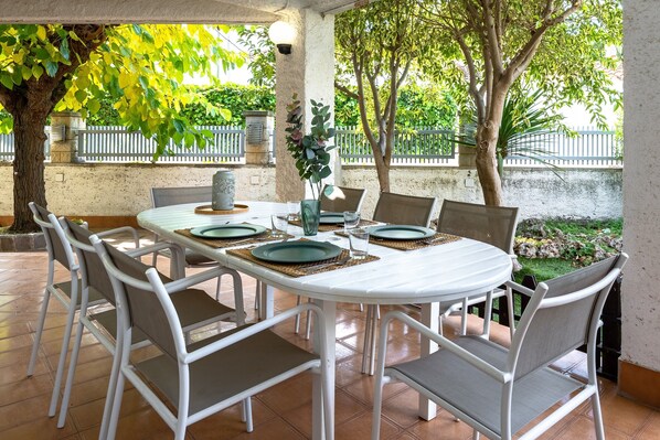 A round table with white chairs, a vase, and a green plate. - Villa 30 m from Cambrils Beach with Sea Views, Wi-Fi, Terraces and Garden (Cambrils)