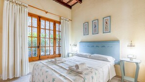 Une chambre à coucher avec un lit, des rideaux, une fenêtre, une table de chevet et des œuvres d’art murales.