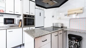 Une cuisine moderne avec des meubles blancs, un plan de travail en granit, un four à micro-ondes, un four traditionnel et un grille-pain.