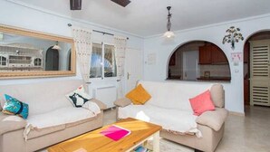 Una sala de estar con un sofá, una mesa de centro y un ventilador de techo.