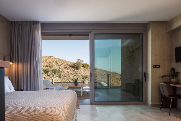 A bedroom with a bed, a desk, a chair, and a sliding glass door leading to a balcony.