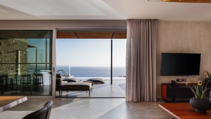 Un soggiorno moderno con una grande TV a schermo piatto, un tavolino in legno e vista sull'oceano.