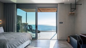 Una camera da letto moderna con un ampio letto, un balcone vista oceano e un design minimalista.