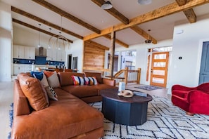 A spacious living room with a sectional sofa, a round coffee table, and a red chair.