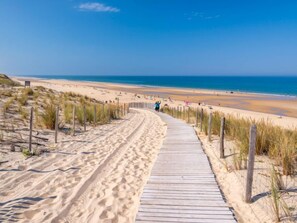 Una platja sorrenca amb un passeig de fusta que condueix a l'aigua.