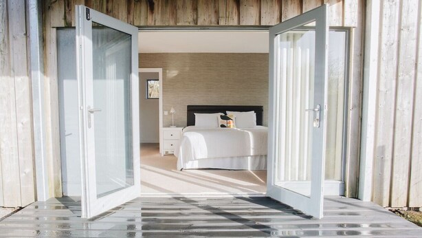 A modern bedroom with a large bed, bedside tables, and a nightstand. - Carnanamish a Luxurious Cottage in Tobermory (Tobermory)