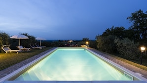Suorakaiteen muotoinen uima-allas, jonka reunat on laatoitettu ja jonka ympärillä on kivestä tehty reunus. Altaan reunalla on aurinkotuoleja ja -varjoja.